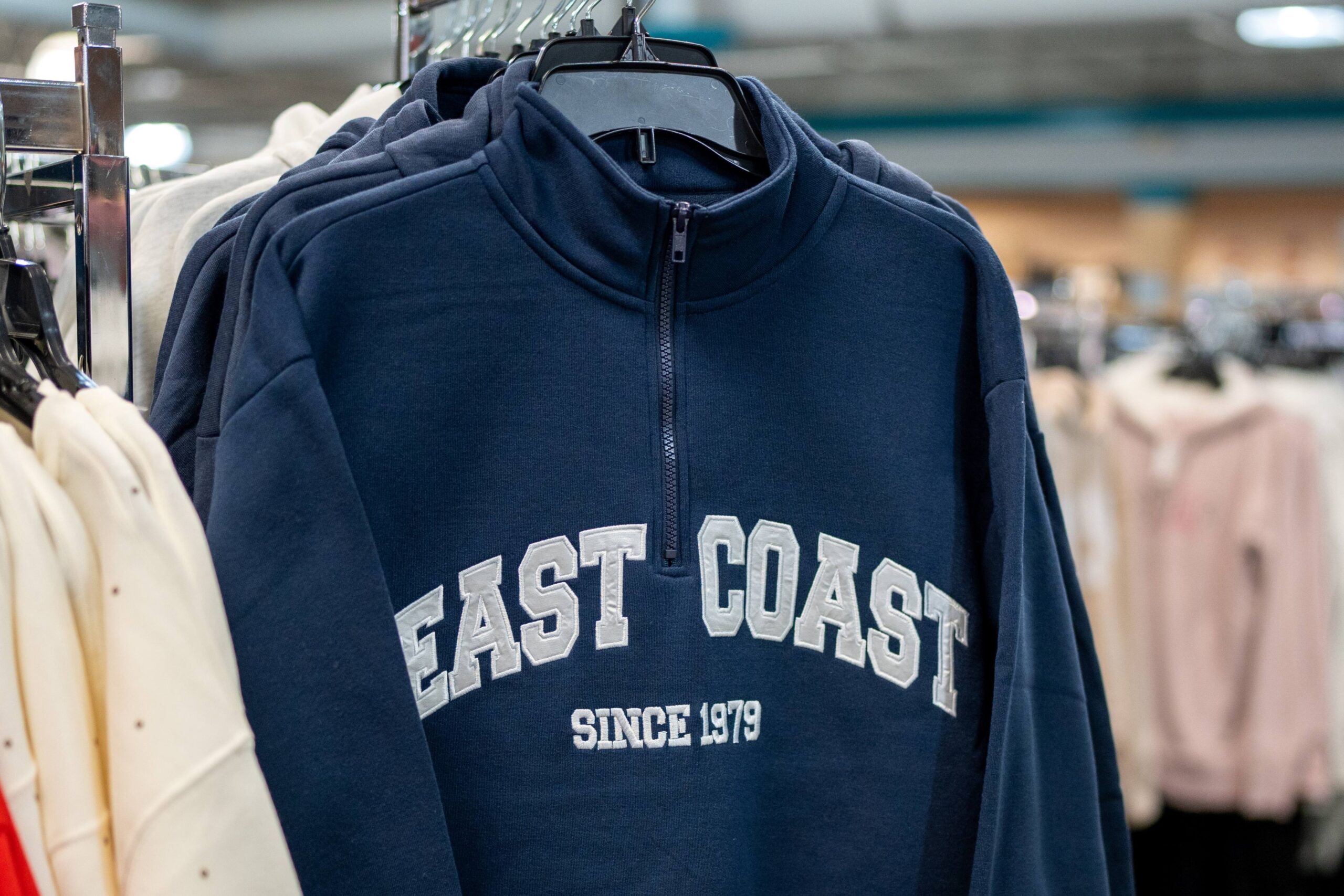 Photo of a quarterzip hanging on a rack with the words East Coast on it